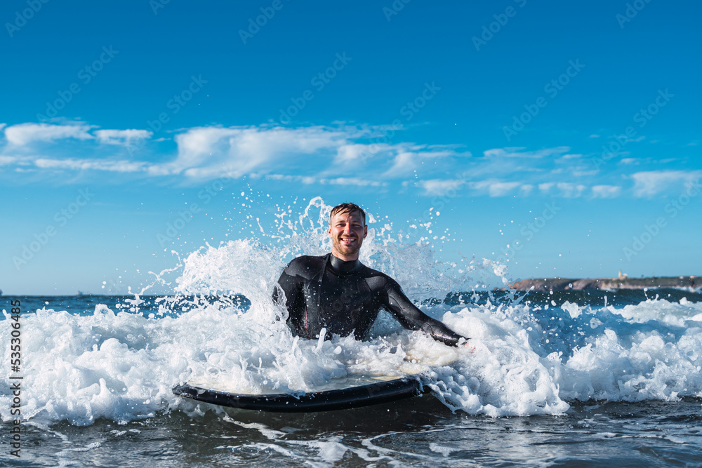 Surfer man smiling in the sea while the force of the sea breaks his back