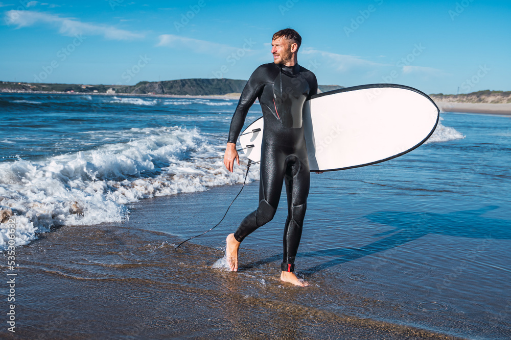 Man getting out of the water after surfing on his favorite beach.