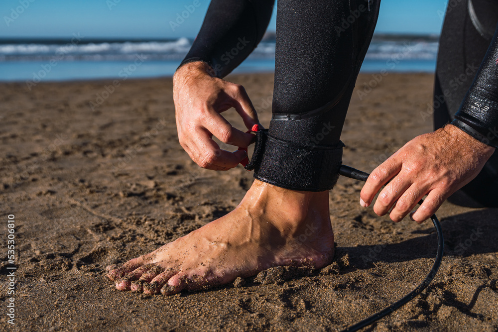 Surfer boy prepares to enter the sea and secures the invention of his surfboard