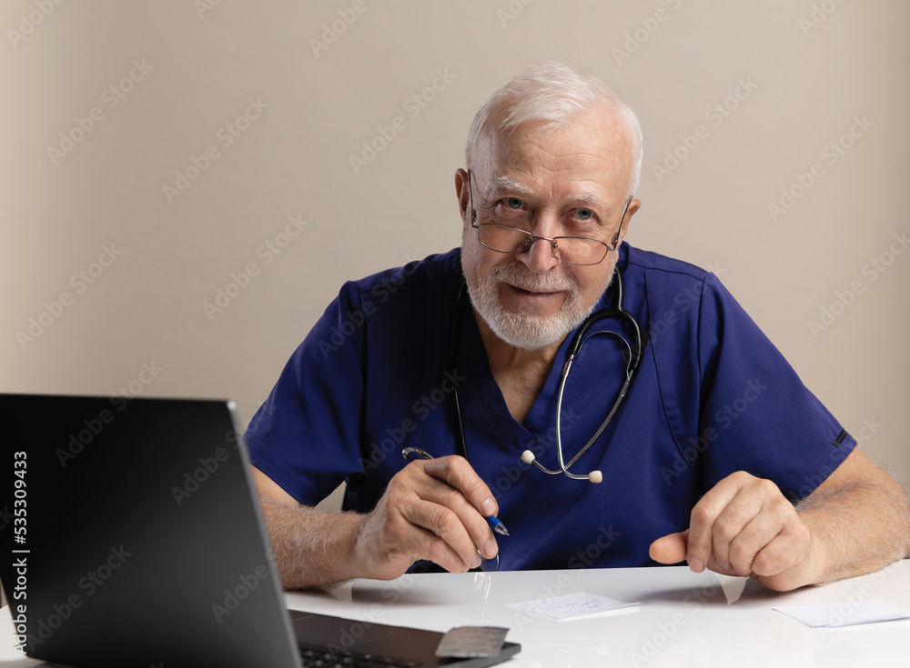 Charismatic elderly man, doctor, sitting in office and writing prescription, wearing glasses with stethoscope, wearing medical clothes on light background, medicine and veterinary concept Charismatic elderly man, doctor, sitting in office and writing prescription, wearing glasses with stethoscope, wearing medical clothes on light background, medicine and veterinary concept