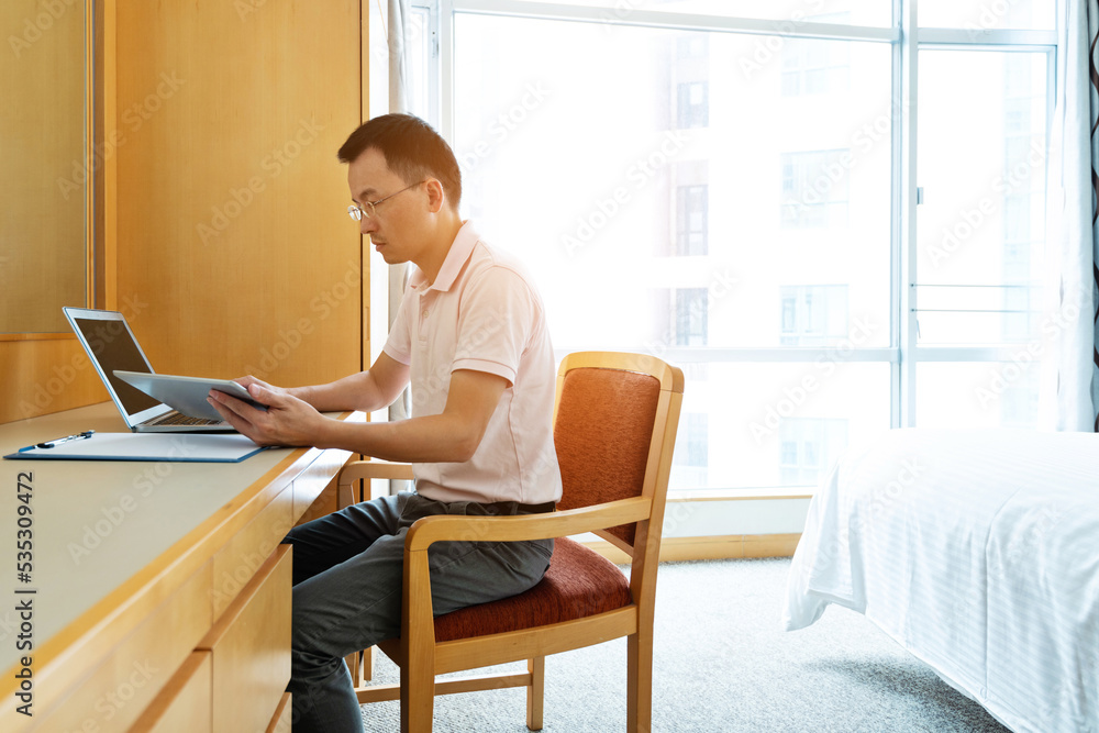 Man using laptop and digital tablet in bedroom Man using laptop and digital tablet in bedroom