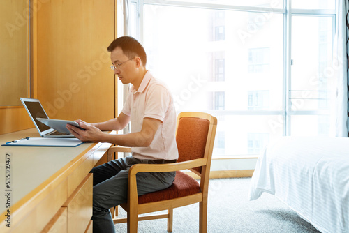 Man using laptop and digital tablet in bedroom
