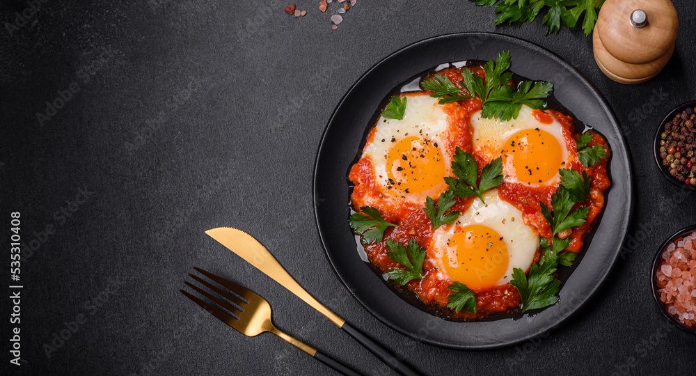Shakshuka, a dish with fried eggs with tomato sauce, sweet pepper, garlic, onions, spices and herbs Shakshuka, a dish with fried eggs with tomato sauce, sweet pepper, garlic, onions, spices and herbs