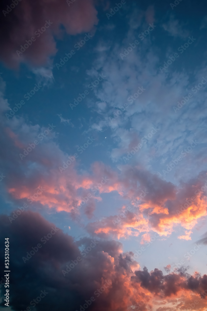 dramatic night sky, with moon and sun bathing the clouds with light, long exposure shot, orange and blue colors, mexico