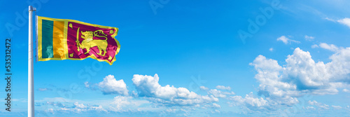 Sri Lanka flag waving on a blue sky in beautiful clouds - Horizontal banner photo
