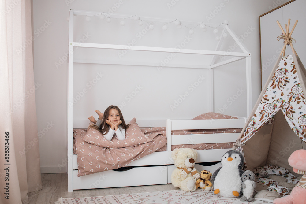 © sofiko14 - Portrait of a beautiful caucasian little girl smiling while relaxing in her bedroom during a leisure day. Cheerful female kid lying on scandinavian wooden house frame bed. © sofiko14 - Portrait of a beautiful caucasian little girl smiling while relaxing in her bedroom during a leisure day. Cheerful female kid lying on scandinavian wooden house frame bed.