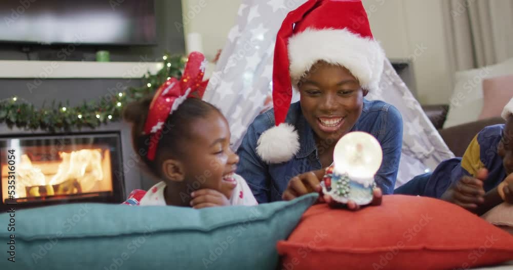 Happy african american mother with daughter playing with snow globe Happy african american mother with daughter playing with snow globe