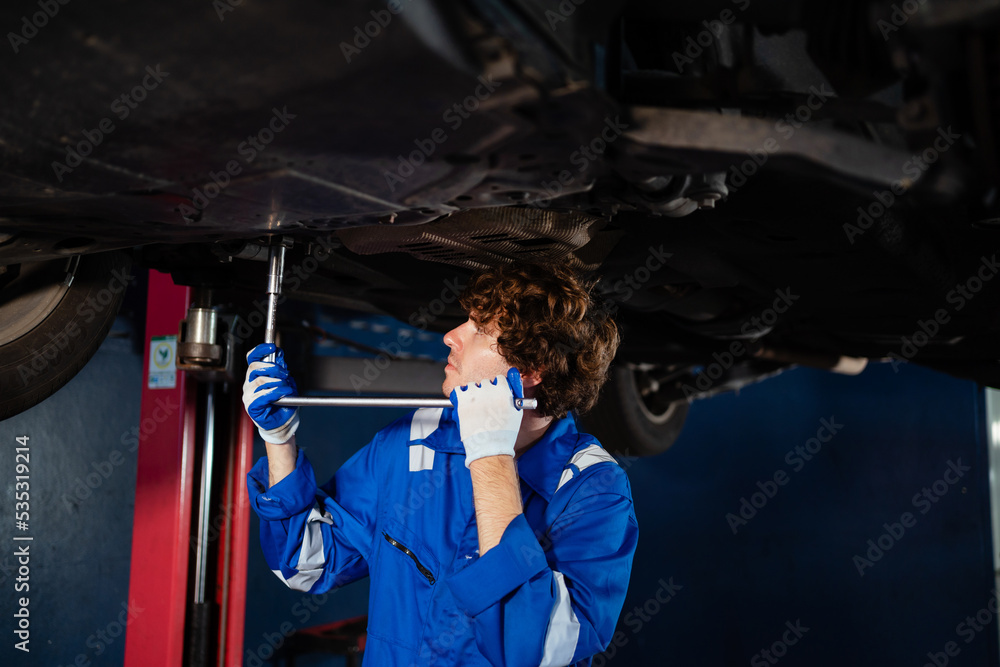 Male mechanic checking the engine system in the car, service, maintenance. Auto mechanic repairing engine. A mechanic is fixing the engine of a car at his factory. Concept of auto service