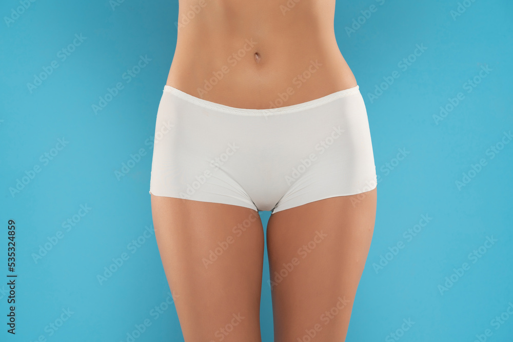 Mid section of woman wearing white briefs, front view on a blue