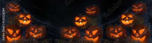 Scary Halloween celebration holiday background banner panorama - Spooky carved pumpkins, spider web and dust in the dark black night