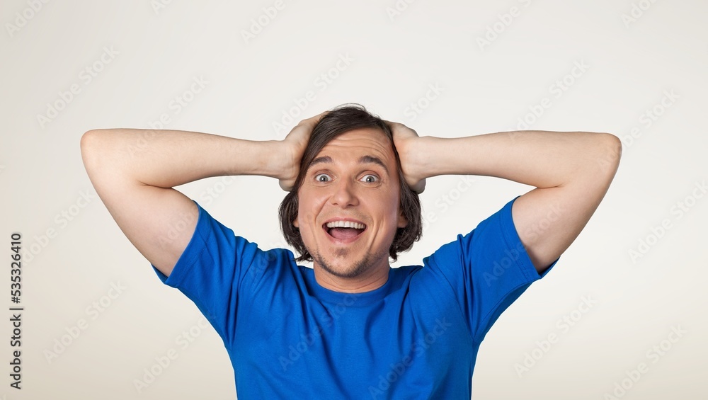 Excited shocked man holding hands on face and screaming looking at camera with big eyes and open mouth, shocked bemused with news, win at lottery on background Excited shocked man holding hands on face and screaming looking at camera with big eyes and open mouth, shocked bemused with news, win at lottery on background