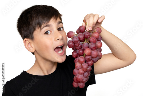 Photo of adorable young happy boy looking at camera.Isolated on the white background. Healthy little boy eating grapes