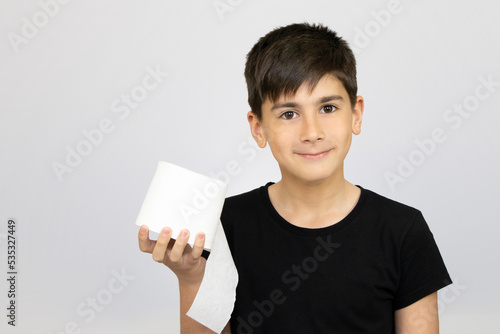 Photo of adorable young happy boy looking at camera. Active boy playing with toilet paper in white background, Child holding White tissue, Children health care concept