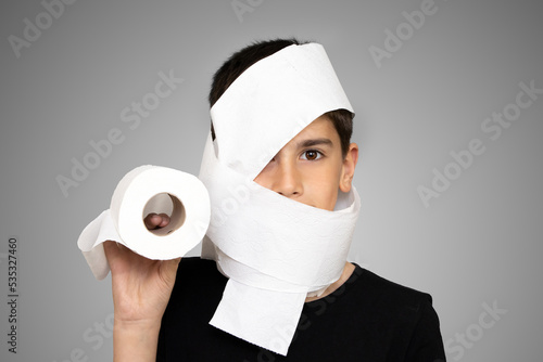 Photo of adorable young happy boy looking at camera. Active boy playing with toilet paper in white background, Child holding White tissue, Children health care concept