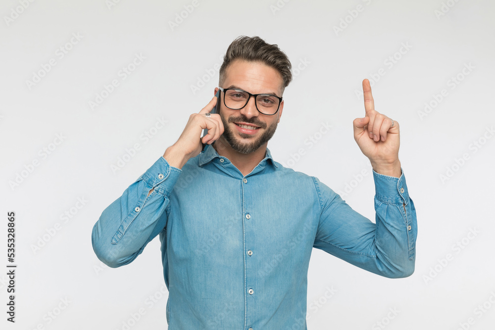 handsome man talking on the phone while pointing up handsome man talking on the phone while pointing up