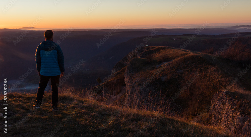 Homme au dessus de la falaise de Mouthier Haute Pierre dans le Doubs le soir avec la lumière d un coucher de soleil 