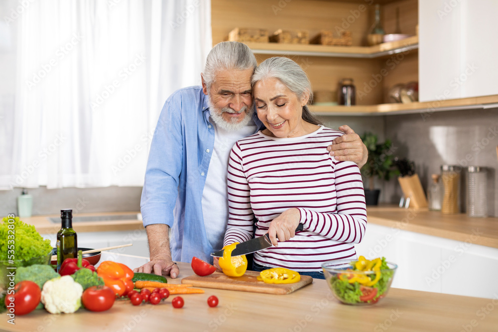 Happy senior couple preparing healthy salad together in kitchen interior Happy senior couple preparing healthy salad together in kitchen interior