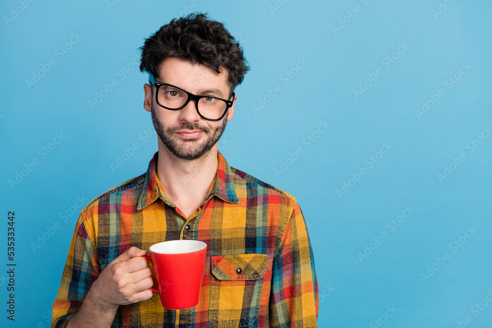 Photo of overworked tired exhausted man in tilted eyeglasses wear plaid shirt holding red cup of coffee isolated on blue color background Photo of overworked tired exhausted man in tilted eyeglasses wear plaid shirt holding red cup of coffee isolated on blue color background