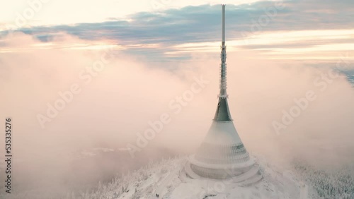 Jested broadcast tower with hotel built on forestry mountain top surrounded with fog cloud. Modern building with spire as symbol of Liberec aerial view photo