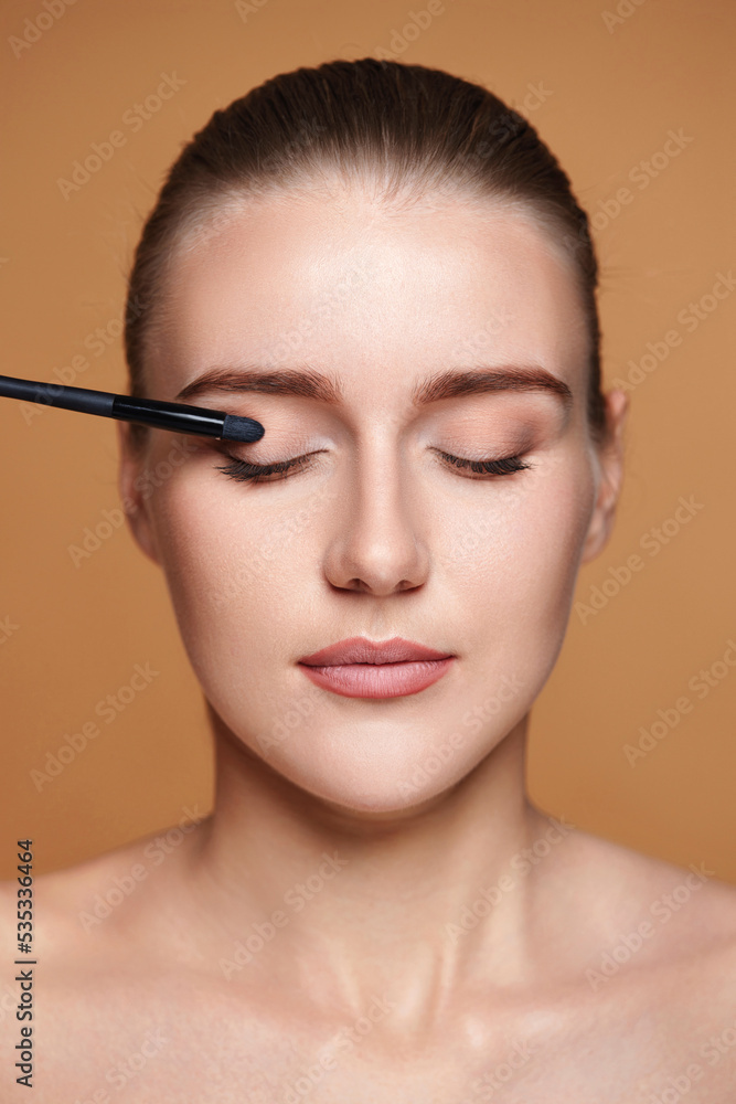 young woman applying eyeshadows on the eyelids young woman applying eyeshadows on the eyelids
