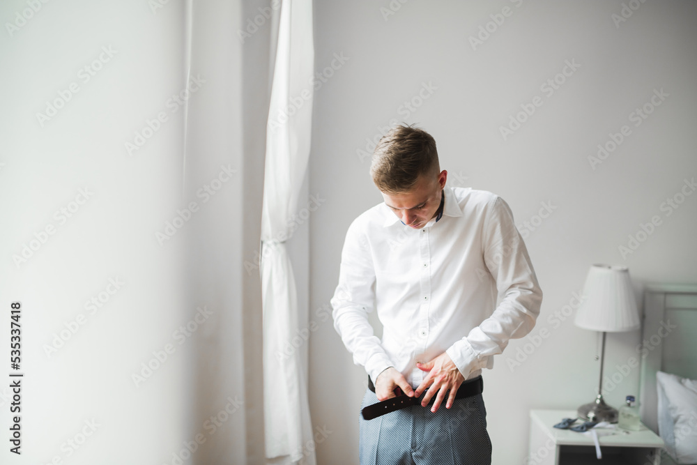 Grooms morning preparation. Handsome man getting dressed and preparing for the wedding Grooms morning preparation. Handsome man getting dressed and preparing for the wedding