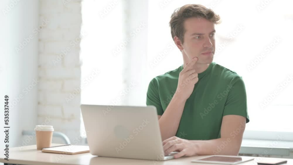 Young Man Thinking while Working on Laptop Young Man Thinking while Working on Laptop