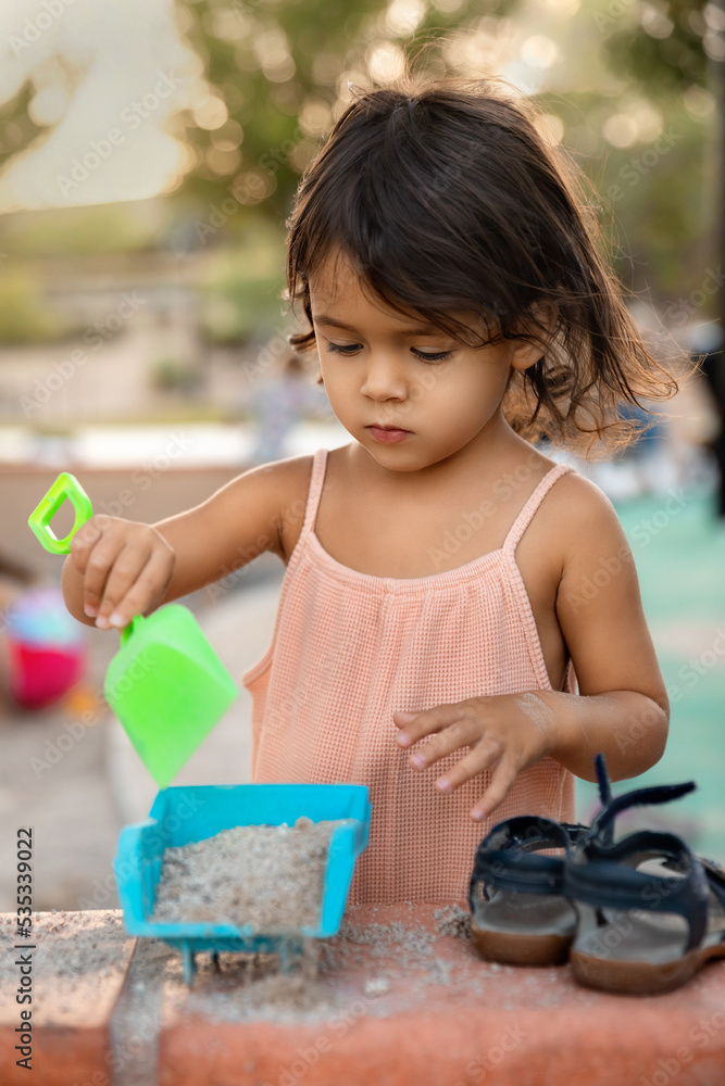 Candid portrait of 2 years old toddler girl playing with sand at playground in the summer, outdoor leisure and childhood concept Candid portrait of 2 years old toddler girl playing with sand at playground in the summer, outdoor leisure and childhood concept