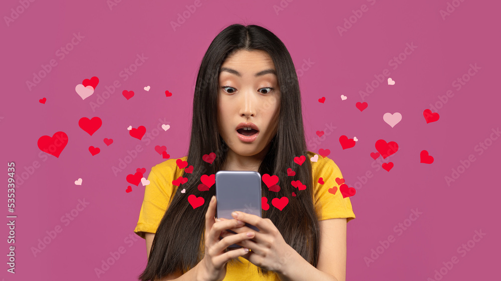 Surprised korean lady looking at smartphone screen with excitement Surprised korean lady looking at smartphone screen with excitement