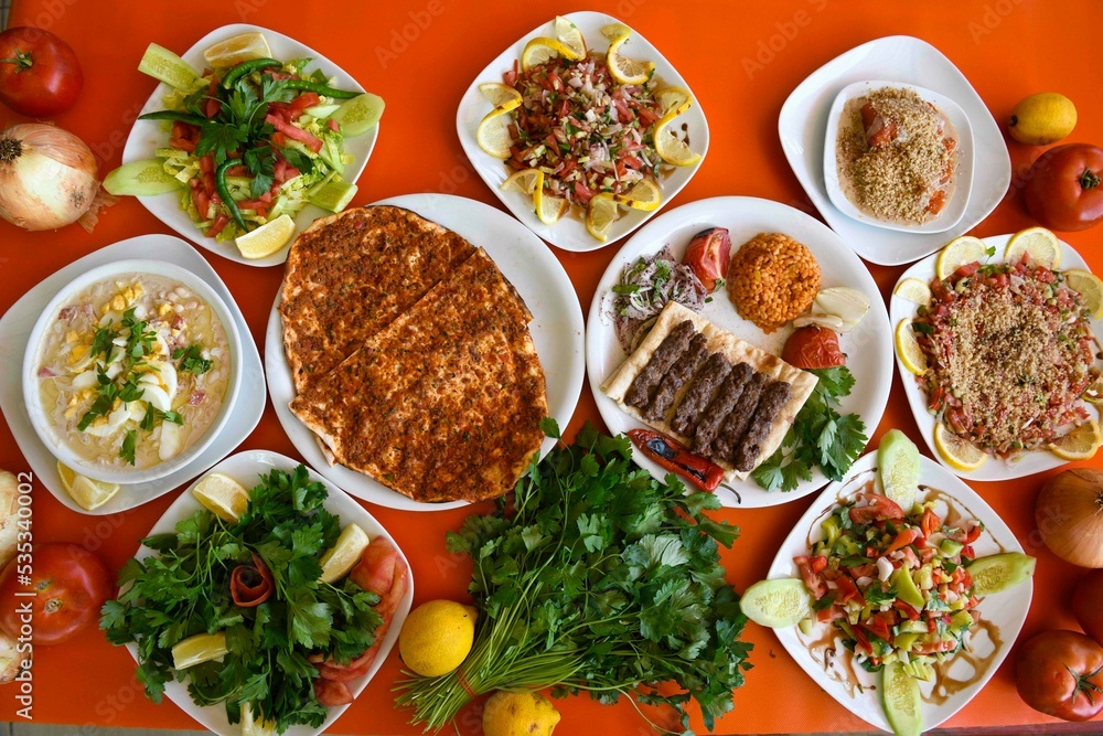 Delicious meat kebab with fresh vegetable salad served with variety of Turkish dishes and appetizers. Top view of assorted Turkish food and meze, tasty and healthy Mediterranean cuisine. Delicious meat kebab with fresh vegetable salad served with variety of Turkish dishes and appetizers. Top view of assorted Turkish food and meze, tasty and healthy Mediterranean cuisine.