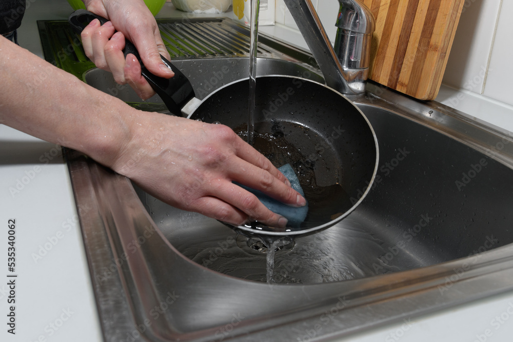 washing the pan in the kitchen under running water