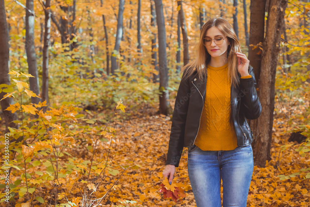 Girl holds fallen leaves and walks in autumn park copy space and place for text. Seasonal concept. Girl holds fallen leaves and walks in autumn park copy space and place for text. Seasonal concept.