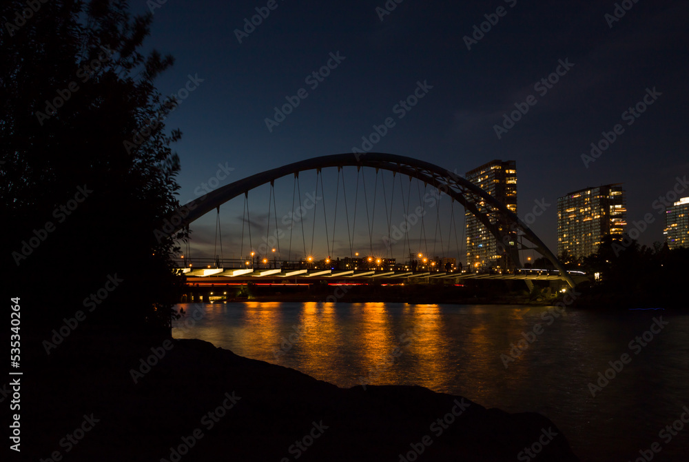 Night city lights - harbor bridge, river, water reflection and evening sky
