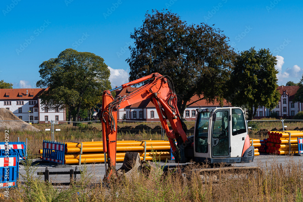Excavator at the construction site. Orange plastic pipes.