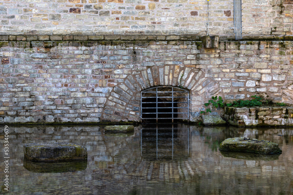 The basement curtained window of an ancient building is reflected in the water.