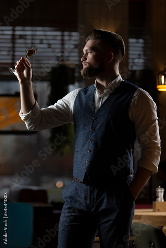 A male sommelier is tasting a drink in a glass. photo