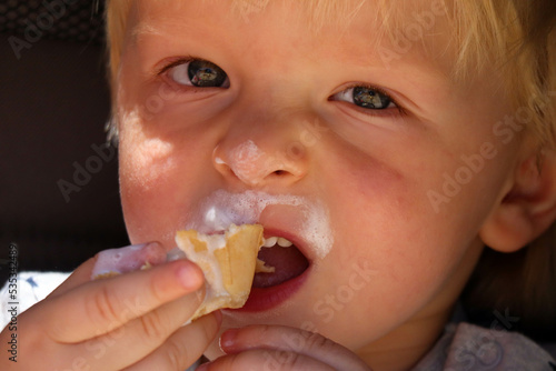 cute blond child eating ice cream close up portrait