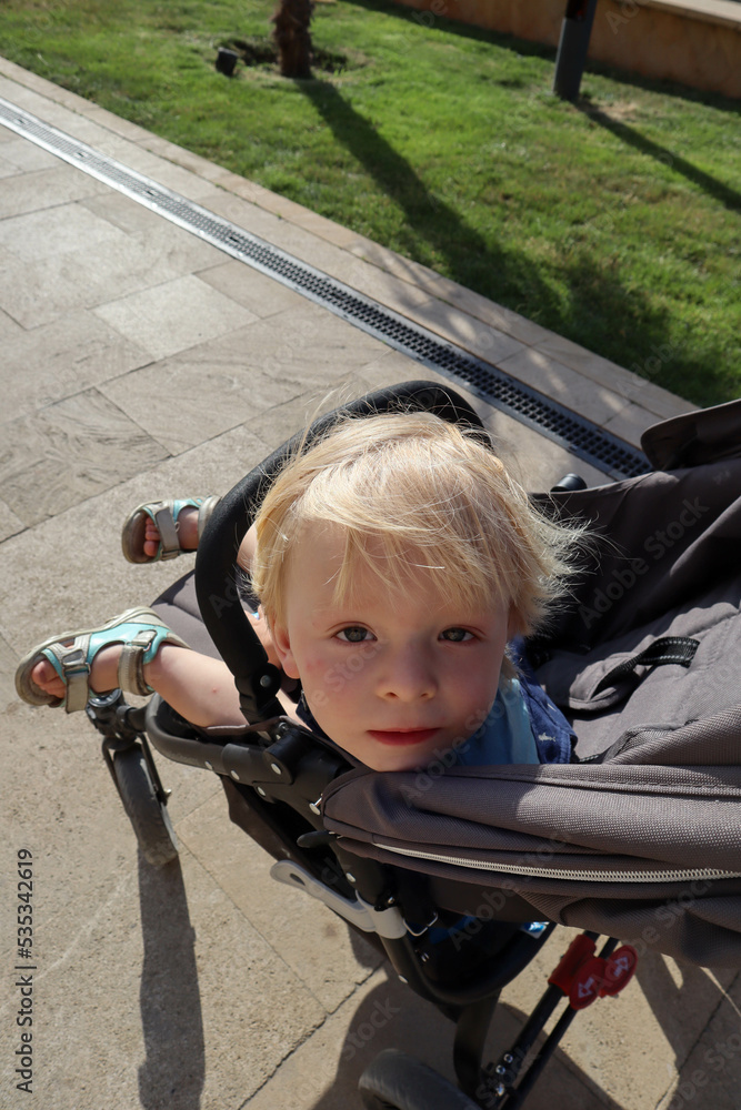 cute blond little boy in a baby carriage portrait close up
