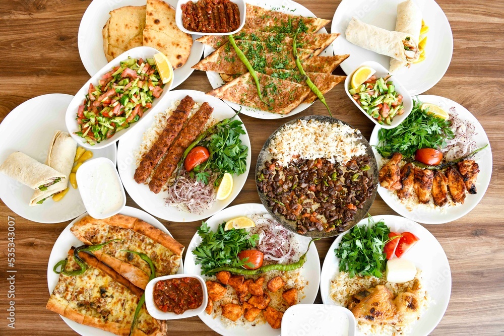 Delicious meat kebab with fresh vegetable salad served with variety of Turkish dishes and appetizers. Top view of assorted Turkish food and meze, tasty and healthy Mediterranean cuisine. Delicious meat kebab with fresh vegetable salad served with variety of Turkish dishes and appetizers. Top view of assorted Turkish food and meze, tasty and healthy Mediterranean cuisine.