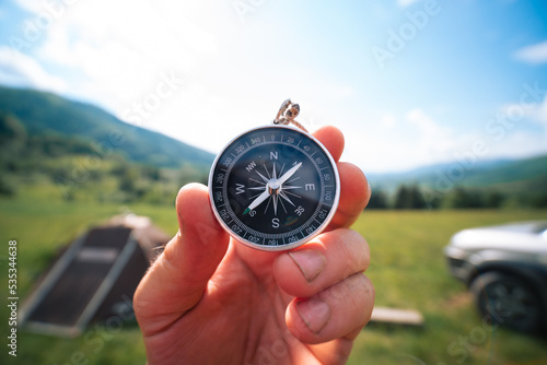 Obraz na płótnie Travel magnetic compass male hand on background of mountain ridge in summer outdoor, point of view. Close up w salonie