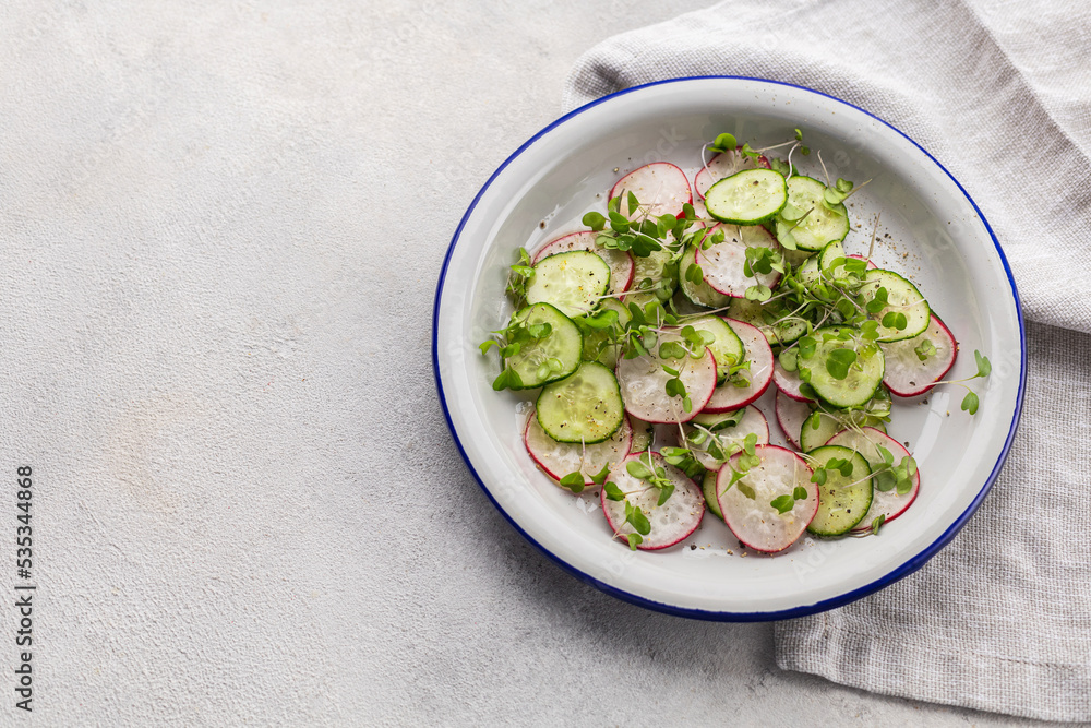 Fresh salad of radish, cucumber and microgreens in a flat plate on a light background with copy space Fresh salad of radish, cucumber and microgreens in a flat plate on a light background with copy space