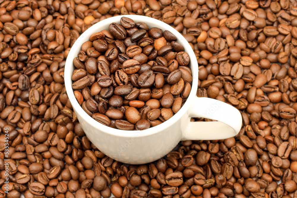 White cup filled with coffee beans on rustic wooden table. Top view. Coffee concept for cafes White cup filled with coffee beans on rustic wooden table. Top view. Coffee concept for cafes