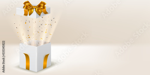Festive illustration with open white gift box with golden ribbons and bow. Pieces of serpentine and rays of light fly out of it