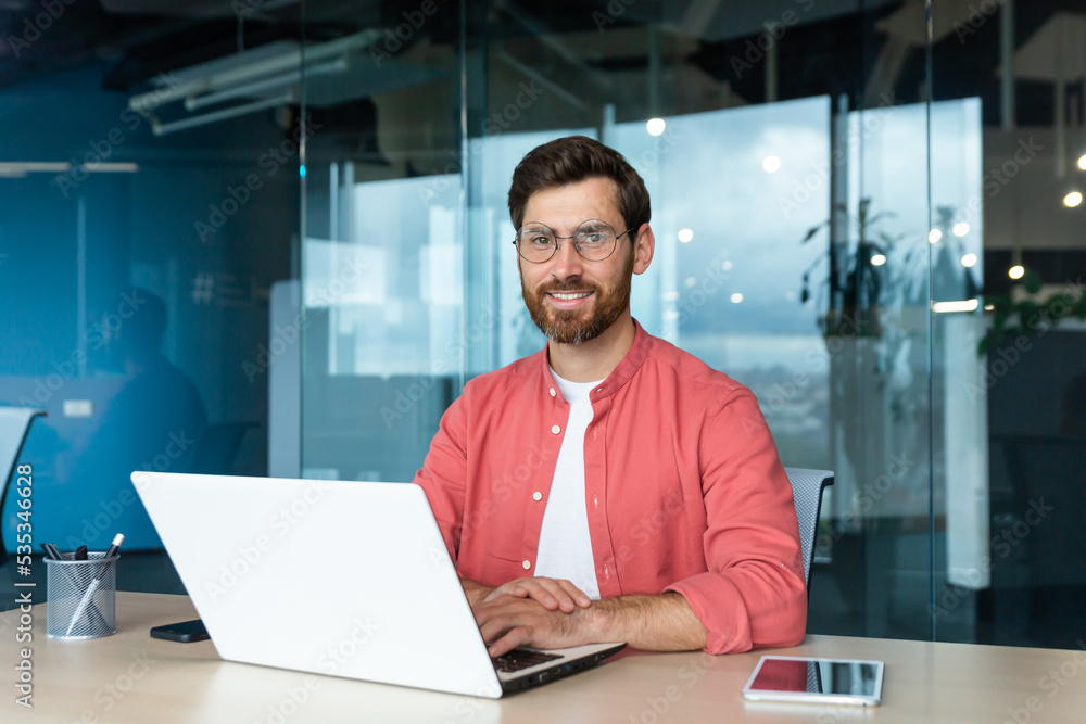 Portrait of mature businessman freelancer startup, bearded man smiling and looking at camera, business owner working inside modern office building wearing red shirt and glasses. Portrait of mature businessman freelancer startup, bearded man smiling and looking at camera, business owner working inside modern office building wearing red shirt and glasses.