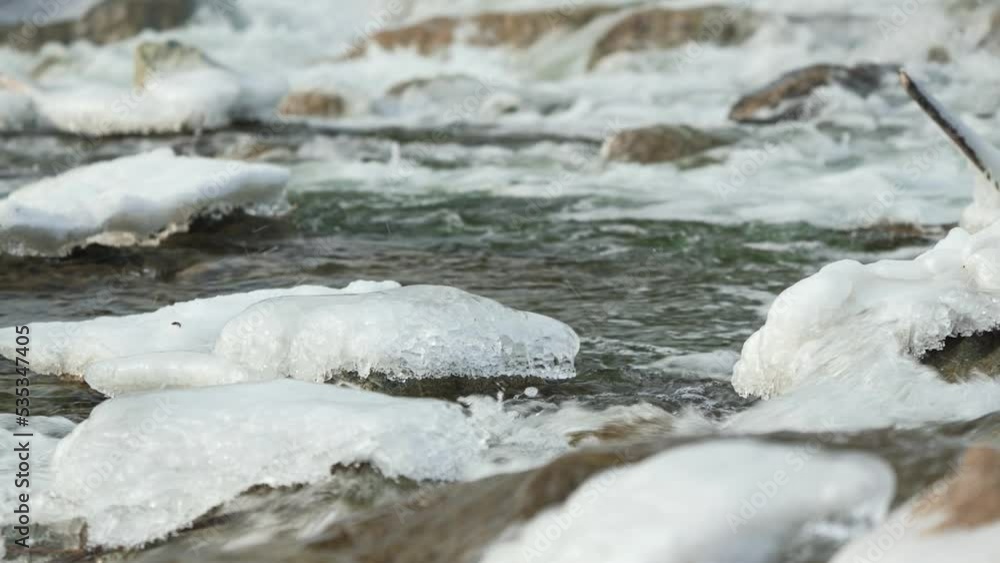 Winter river flowing near snow and ice covered stones Winter river flowing near snow and ice covered stones
