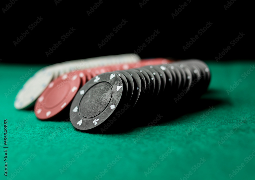 Poker game concept. Casino Concept for business risk chance good luck or gambling. Stack of Poker chips, poker chips stack on a green gaming poker table, black background. soft focus Poker game concept. Casino Concept for business risk chance good luck or gambling. Stack of Poker chips, poker chips stack on a green gaming poker table, black background. soft focus