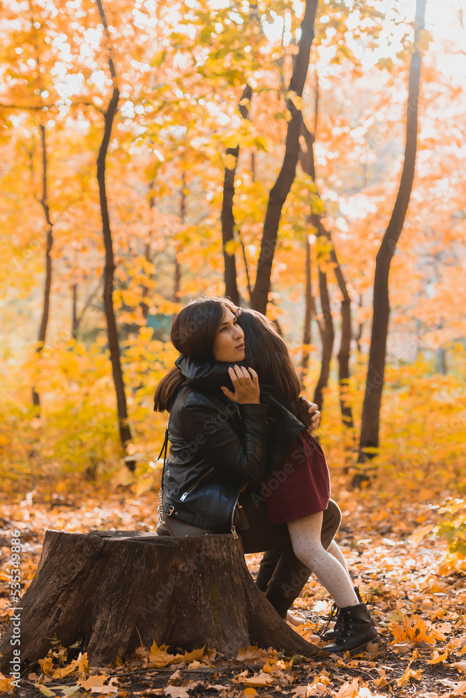 Mother and daughter spend time together in autumn yellow park. Season and single parent concept.