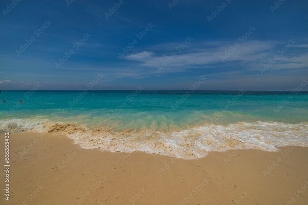 Beautiful view of rolling turquoise wave on sandy beach in Atlantic ocean on island of Aruba.