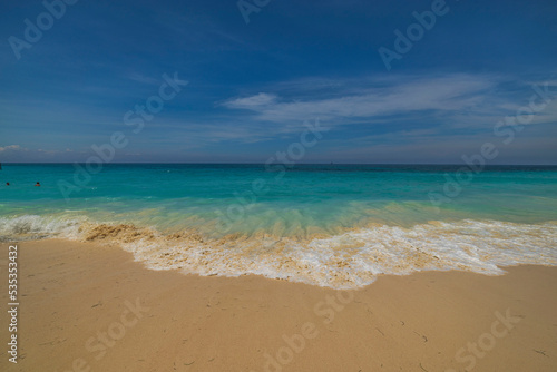 Beautiful view of rolling turquoise wave on sandy beach in Atlantic ocean on island of Aruba.