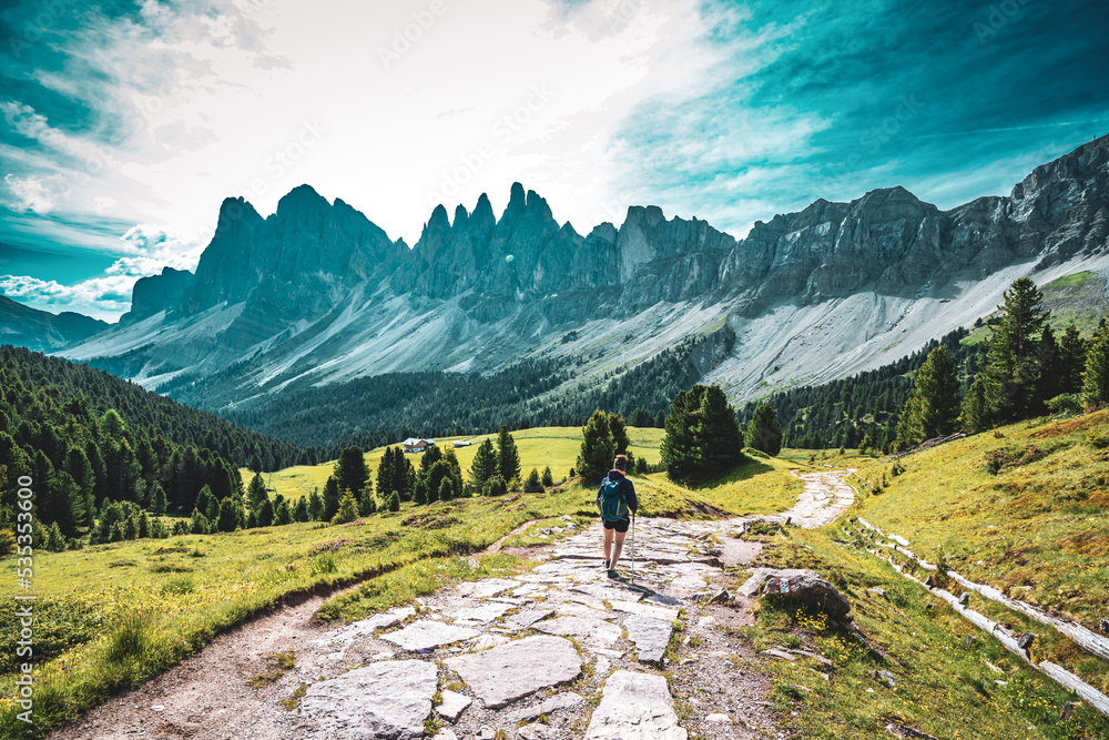 Athletic woman walks along beautiful hike trail at Seceda in the dolomites at noon. Seceda, Saint Ulrich, Dolomites, Belluno, Italy, Europe.