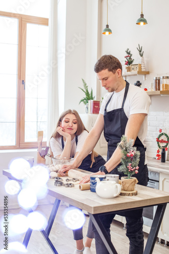 Young happy couple enjoying and preparing christmas cookies together in their kitchen.